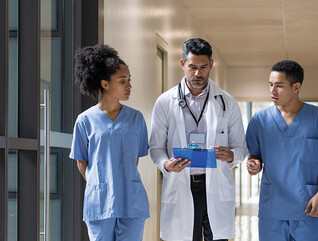 Doctor holding clipboard walks with medical students