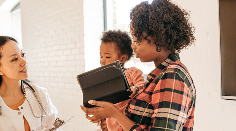  Family doctor attending toddler with iPad