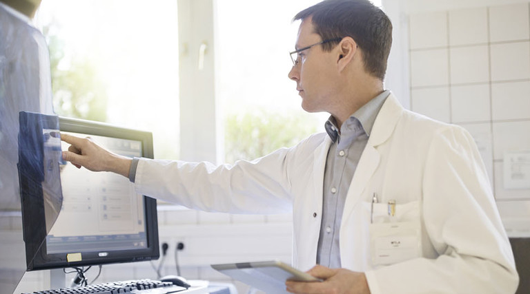 Male doctor using computer with tablet