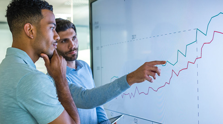 Businessman explaining line graph to his coworker.