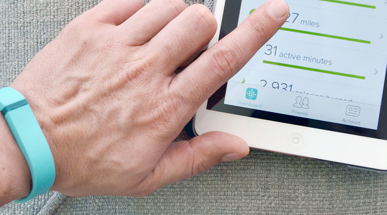 Close up of a man wearing a Fitbit Flex using the App on an iPad Mini