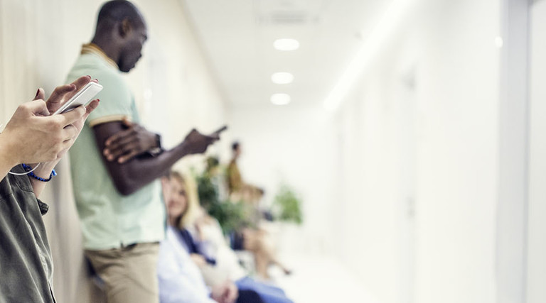 Patients using mobile phone in waiting room of clinic.