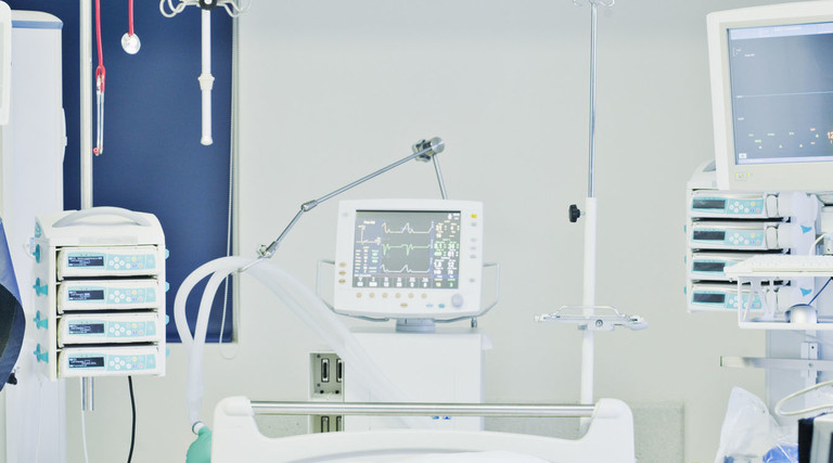 Empty hospital bed in intensive care with monitors all around