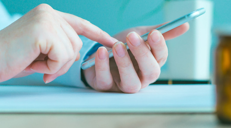 General practitioner using smartphone in office