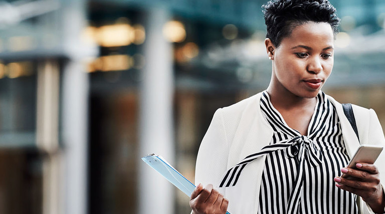 Shot of a young businesswoman using a mobile phone on the go in the city