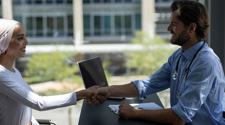 Disabled mixed-race woman shaking hands with Caucasian male doctor