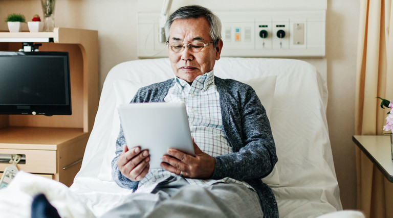 Man Reading on iPad in Hospital Room