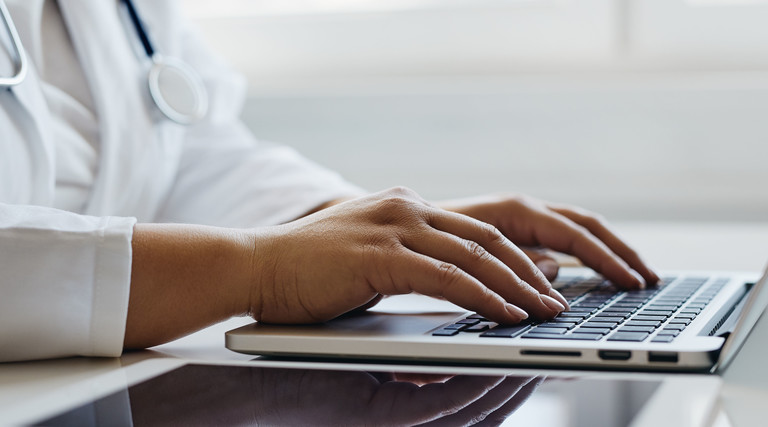 Doctor types on computer