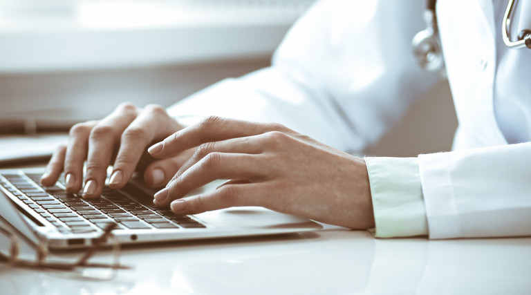 Doctor types on laptop