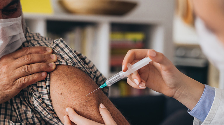 Health worker injecting a vaccine into a patient's arm.