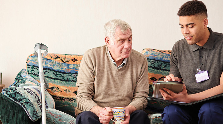 Patient and caregiver conferring over a tablet