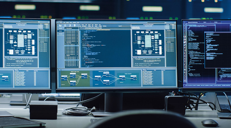 three computer monitors with code