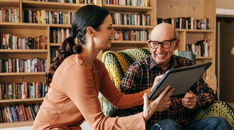 caregiver and senior use tablet together