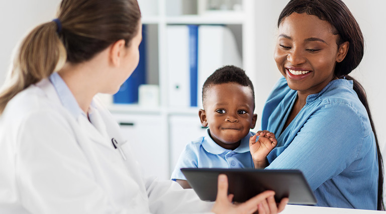 doctor shows information on a tablet to mom holding baby