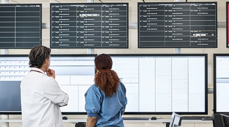 Nurse and doctor consider information on multiple screens