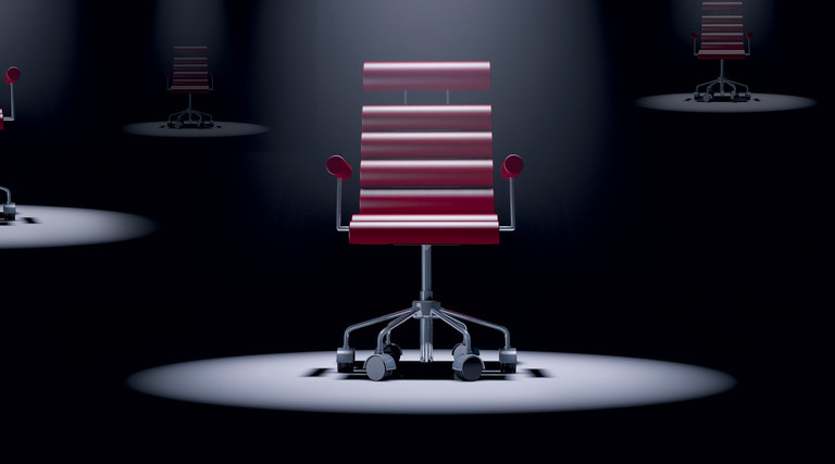 red office chair spotlit in a dark room