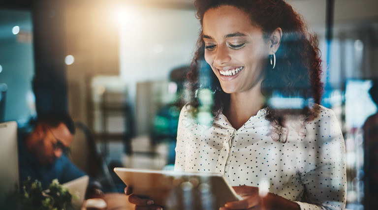 smiling woman looks at tablet in office