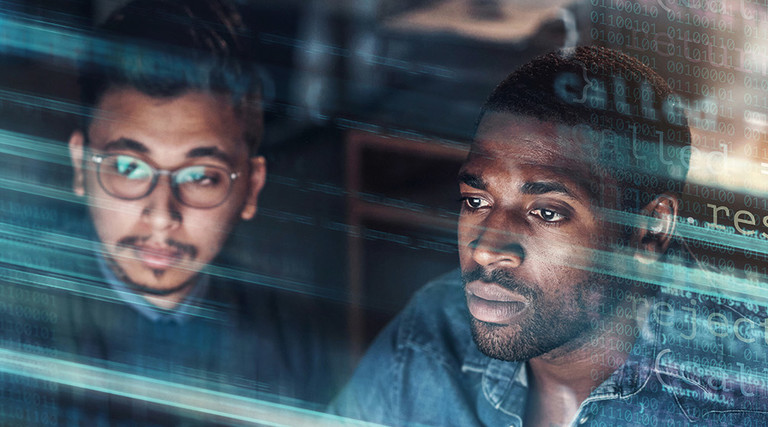 two IT staff look at monitor concerned with blue code on top of the image