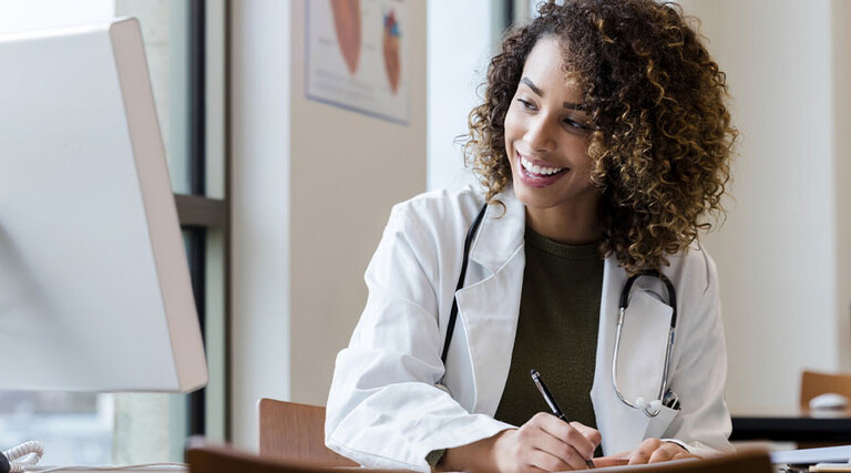 Doctor writing information from computer