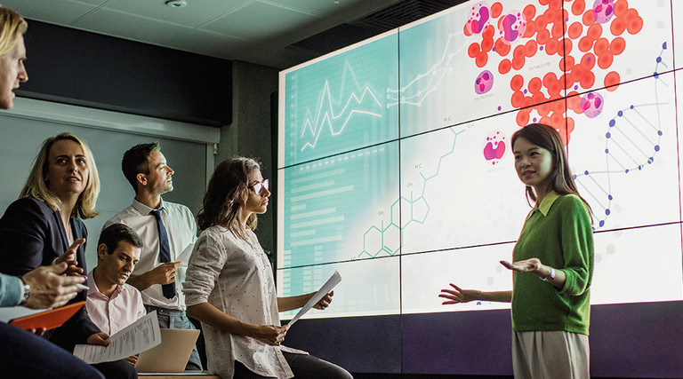 group of scientists look at medical information on a large screen