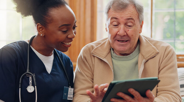 nurse and senior laugh while looking at tablet