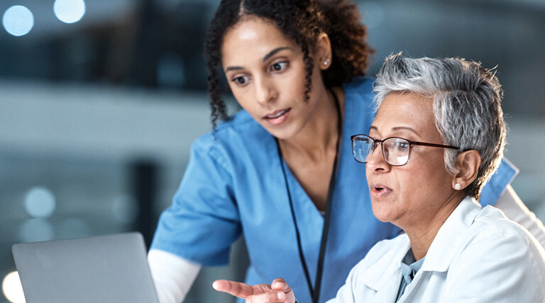 two clinicians looking at laptop