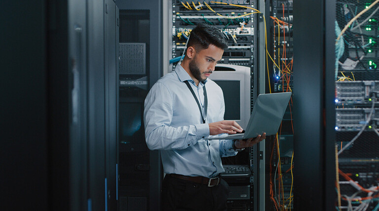 man on laptop in server room