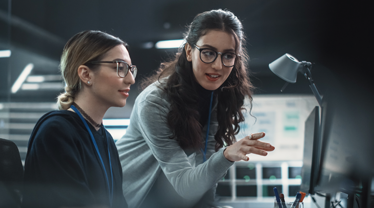 two IT leaders discuss cybersecurity in front of computer