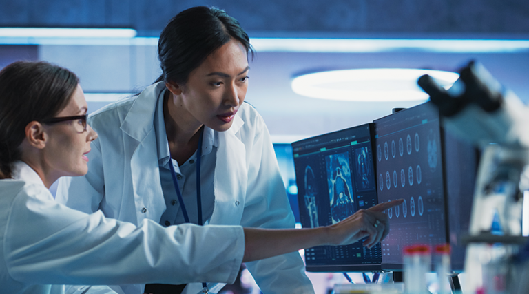 medical researchers looks at images on a monitor in a lab