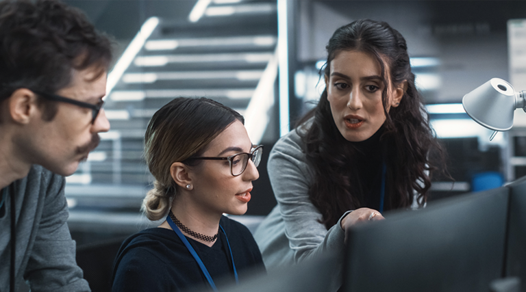 cybersecurity team members talk in front of monitors