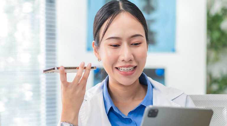 Doctor using phone to dictate to tablet