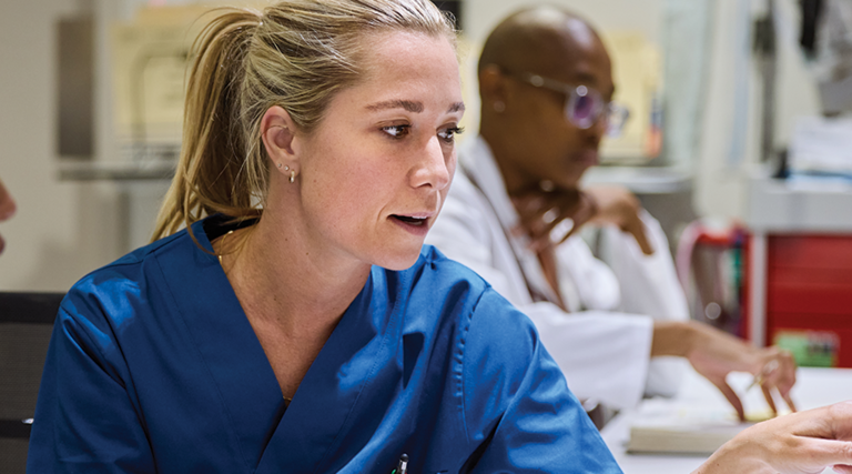 nurses talk in front of desktop computer