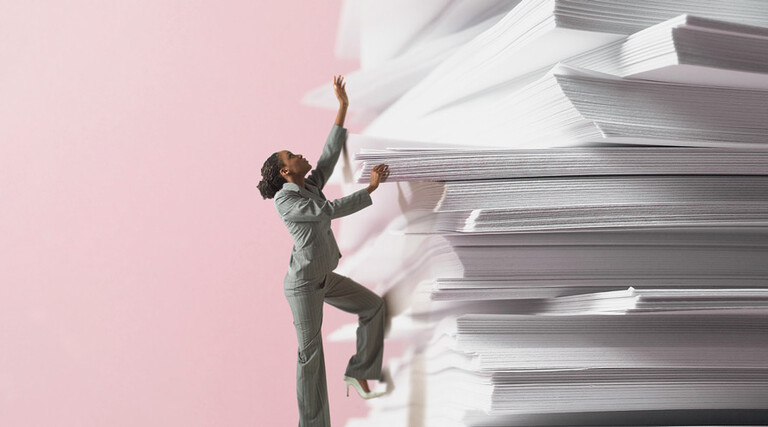 miniature woman climbs up stack of papers