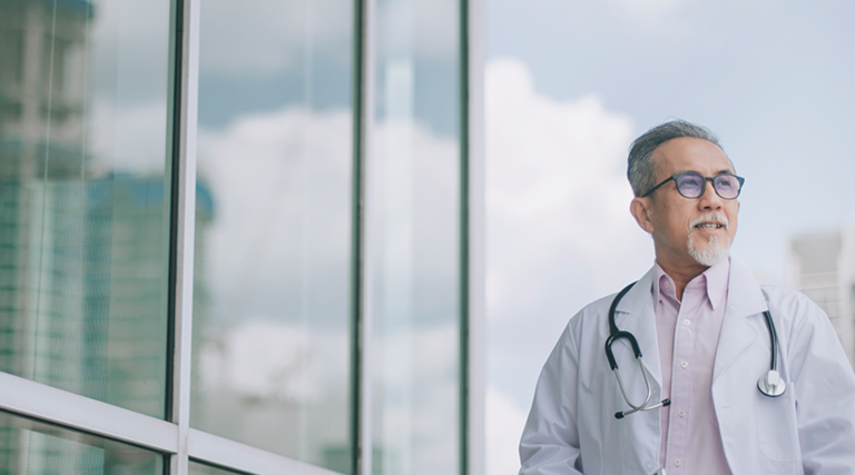 doctor in front of clouds and reflective building