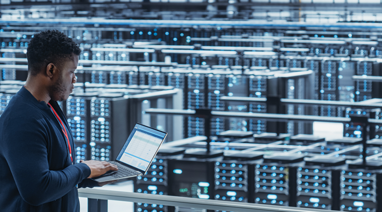engineer with laptop overlooking data center