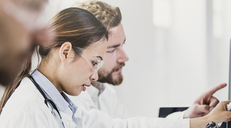 medical researchers look at data on desktop monitor