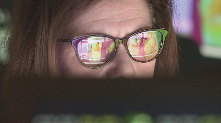 woman wearing glasses looking at healthcare data on screen