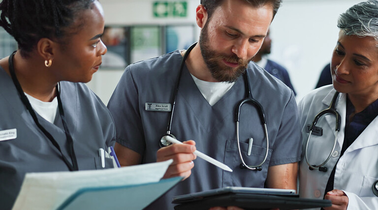 Team of clinicians talk over tablet