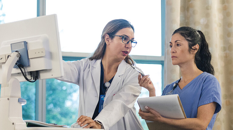 doctor shows intern AI features in an EHR on computer