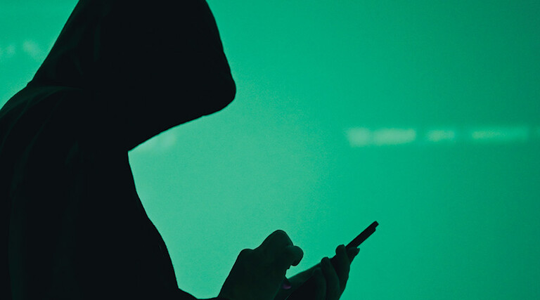 silhouette of hooded figure on phone