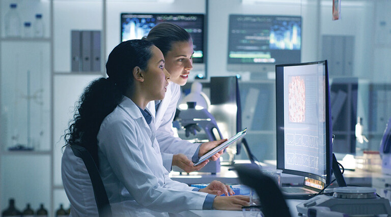 two researchers look at medical data on computer in lab