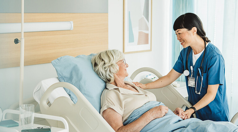 nurse cares for senior in hospital bed