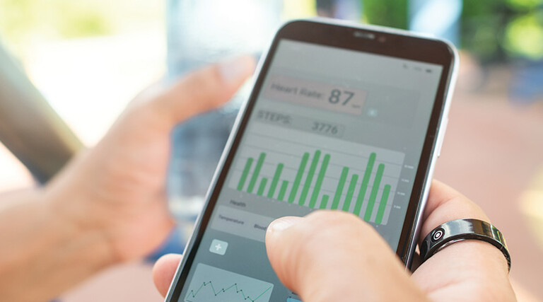 person with wearable ring checks app on phone