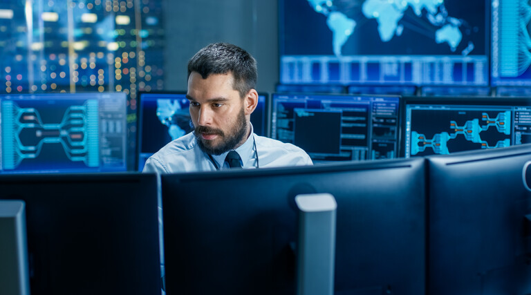 man surrounded by monitors with security data