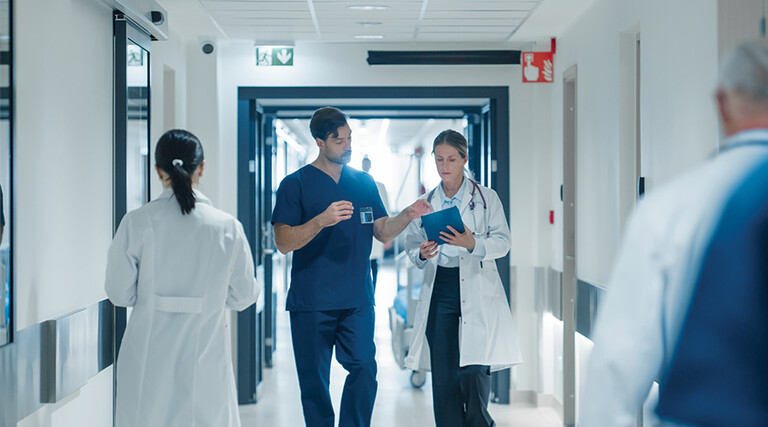 clinicians walk down busy hospital hallway