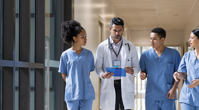 Doctor holding clipboard walks with medical students