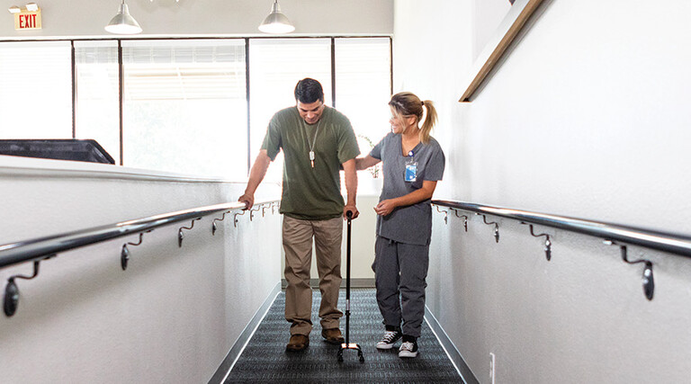 nurse helps veteran walk for rehab