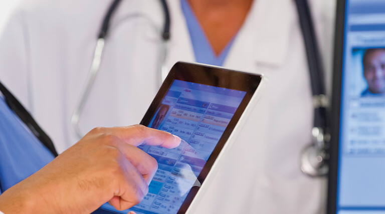 nurse and doctor look at EHR on tablet and monitor