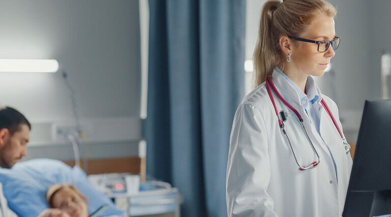 doctor looks at data on computer at the bedside