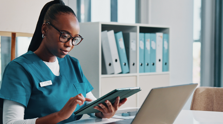 nurse using tablet and laptop at desk